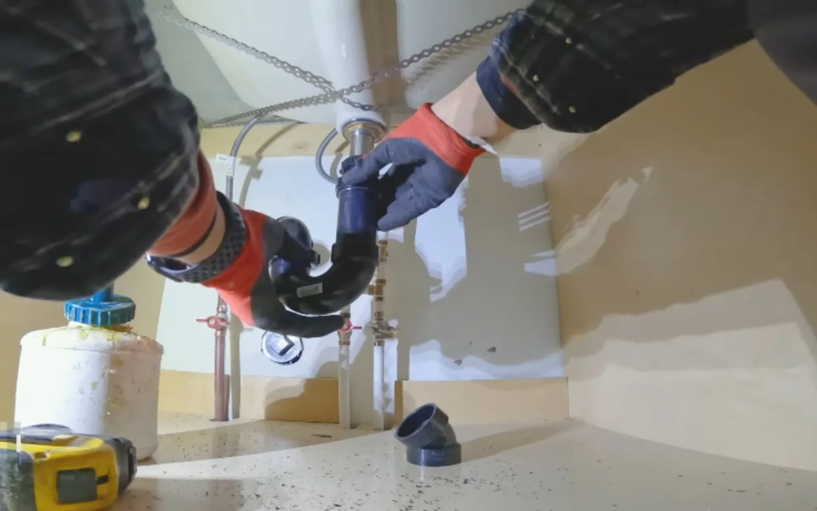 Plumber repairing a P-trap and drain connection under a bathroom sink