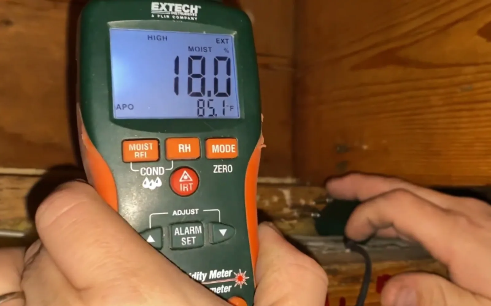 Plumber using acoustic leak detection equipment against a wall